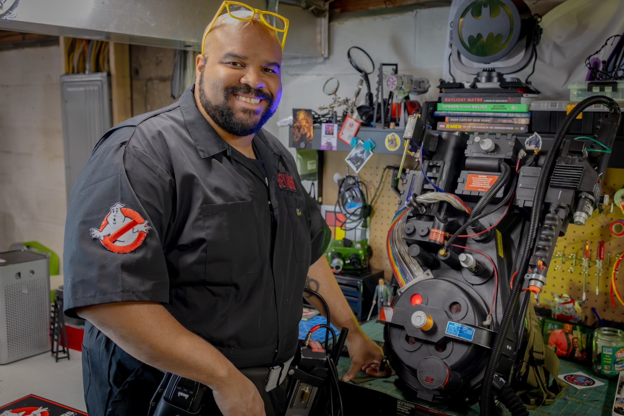Archer standing beside a proton pack build in his workshop