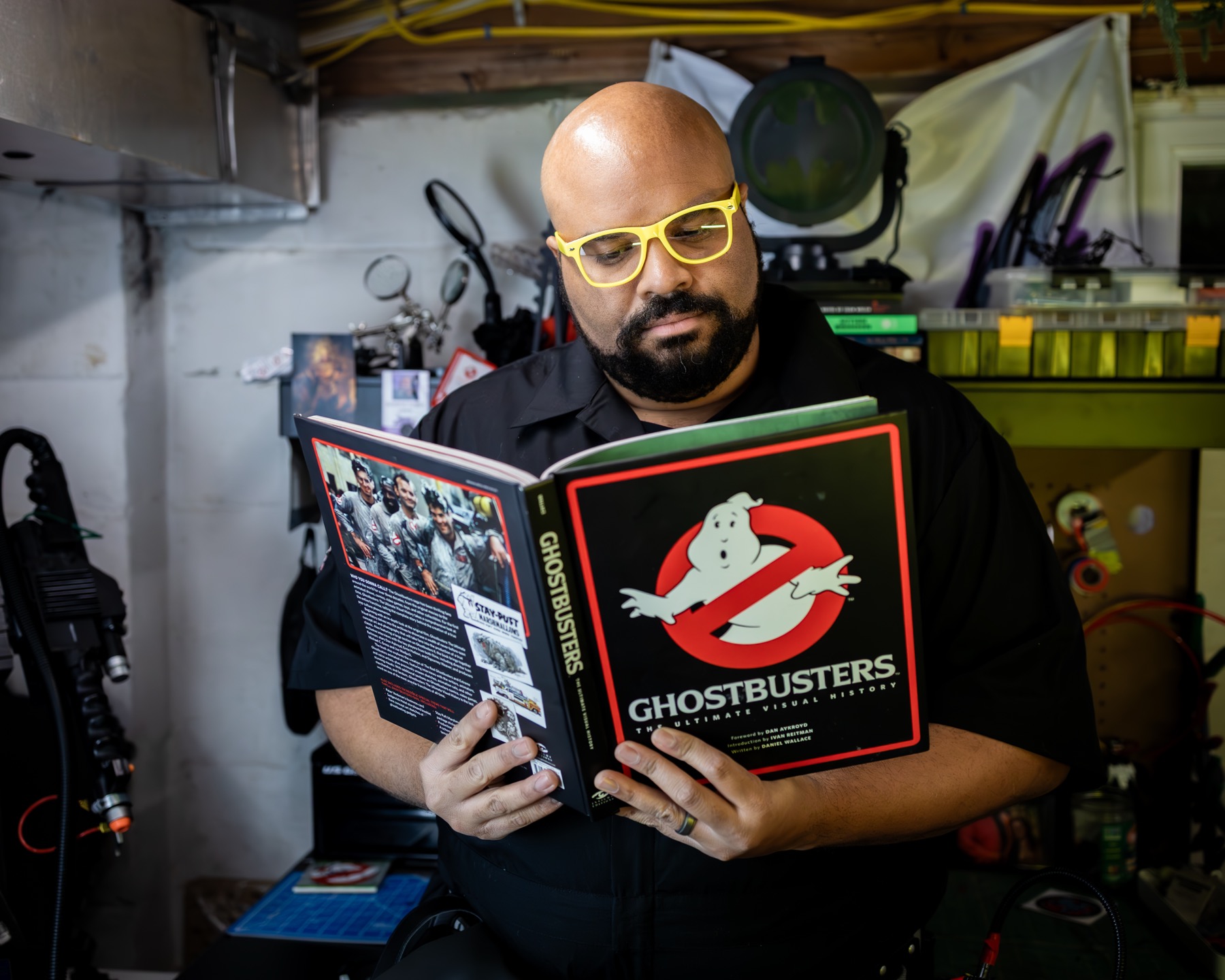Archer reading Ghostbusters: The Ultimate Visual History in his workshop