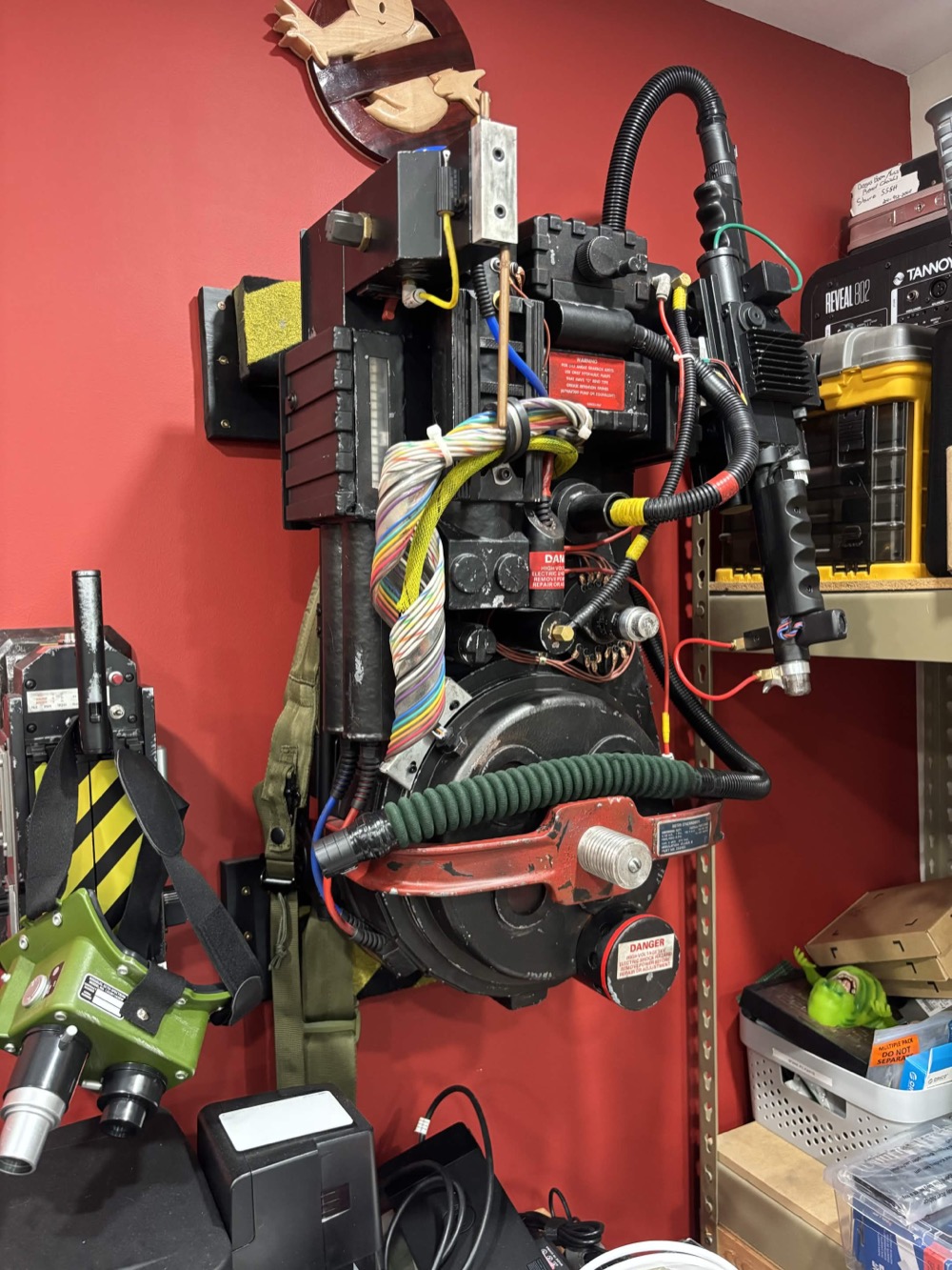 Completed weathered proton pack hanging on a red wall