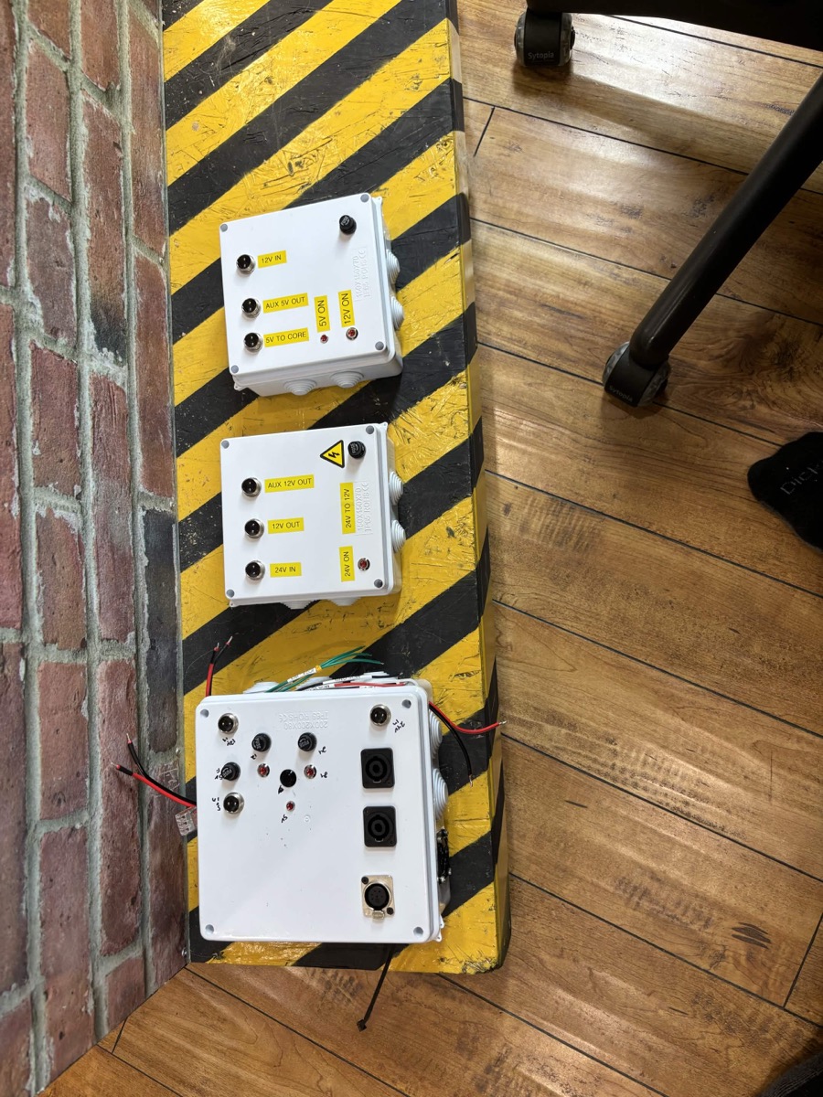 White labeled power boxes on a caution-striped base