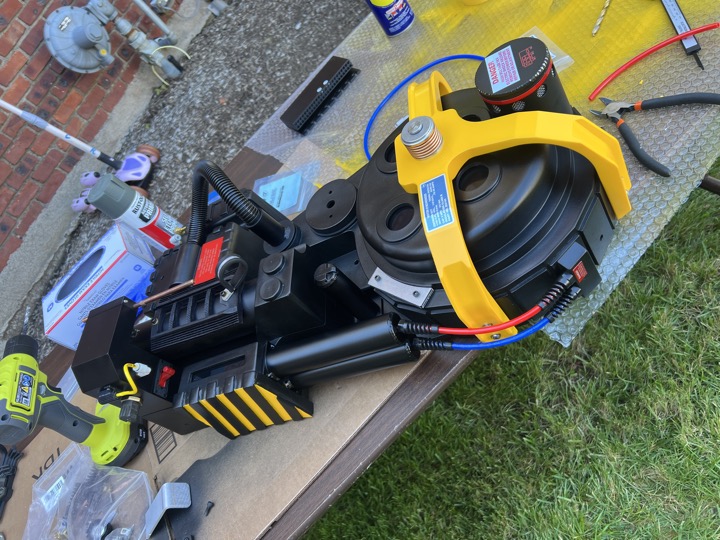 Proton pack laid out on an outdoor workbench with tools and supplies.