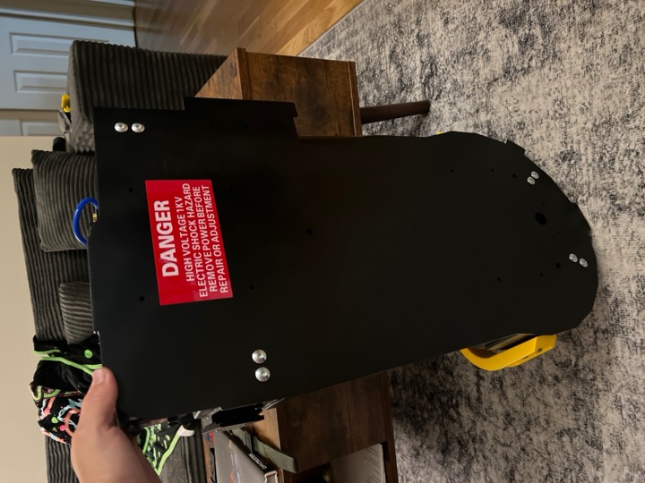Black backplate with mounting hardware and a red warning label.