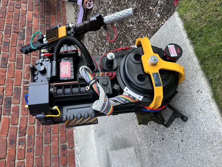 Finished proton pack outdoors, with yellow accents, ribbon cable, and attached wand.