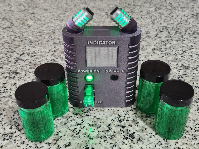 Illuminated prop with green lights and four green sample jars.