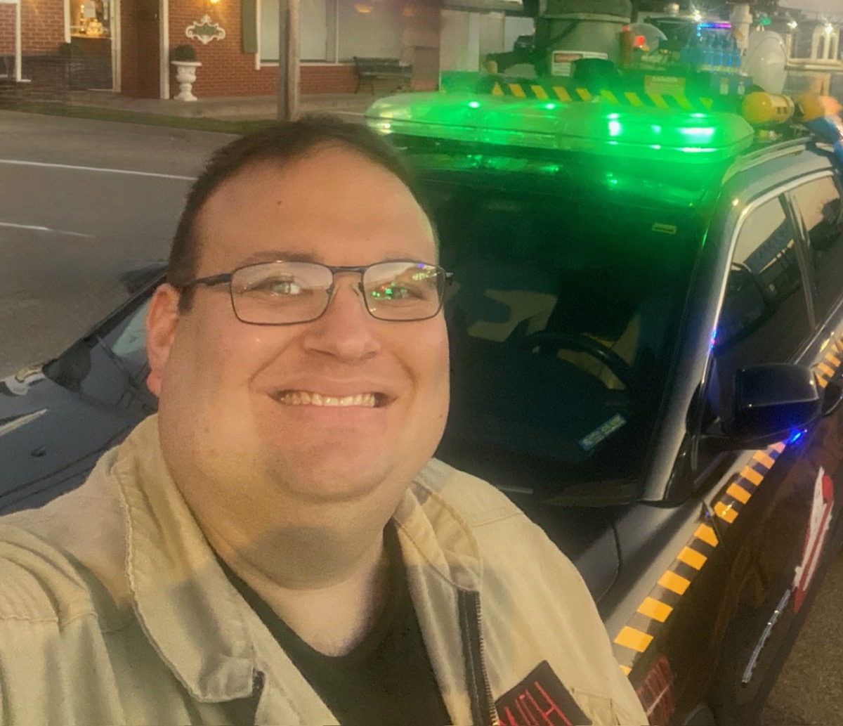 Grant smiling beside a Ghostbusters-inspired vehicle with glowing green roof lights