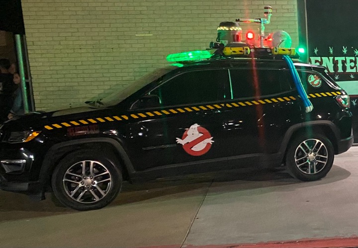 Ghostbusters-inspired black SUV with illuminated roof equipment and green lights.